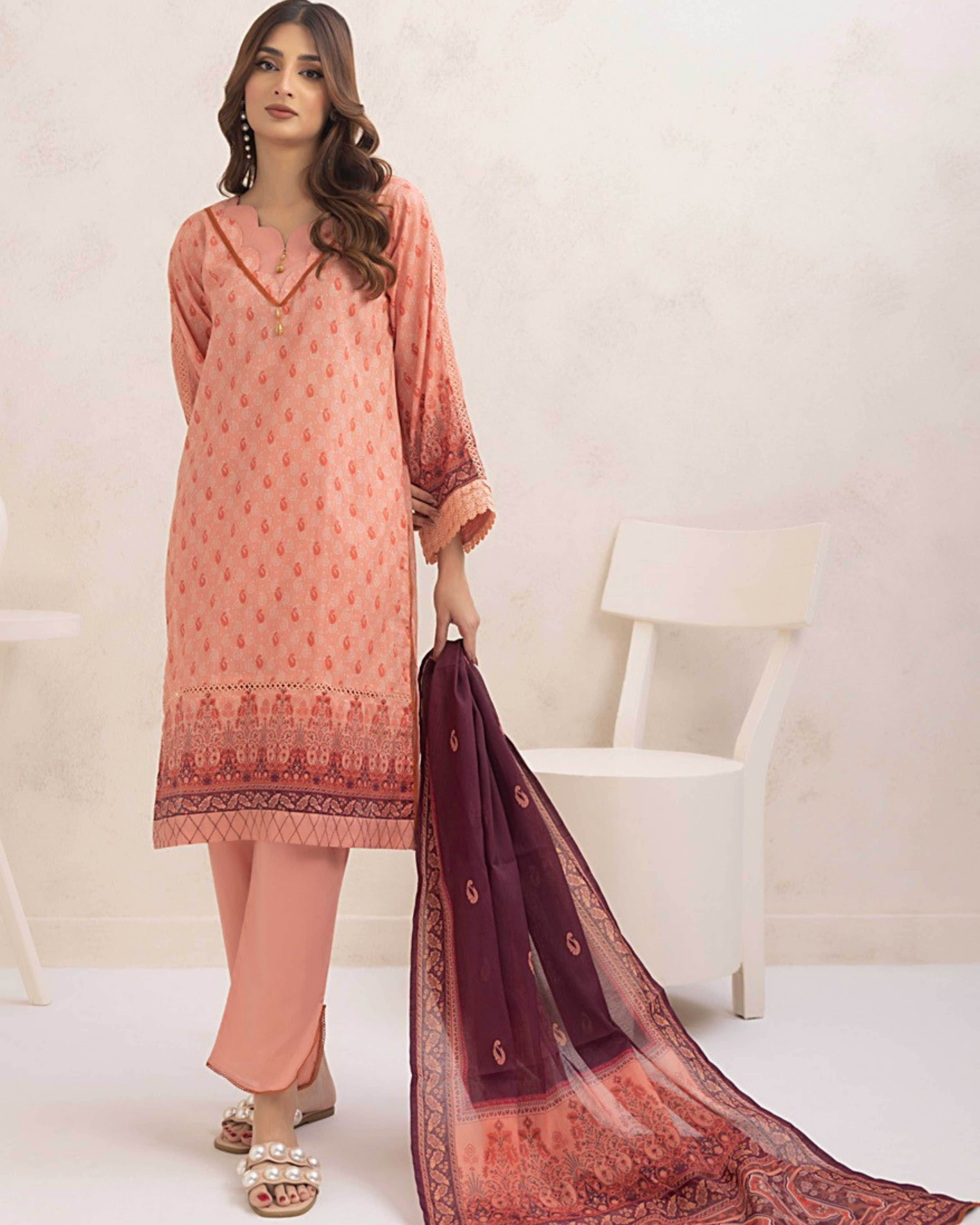 Woman wearing a peach-colored traditional outfit with a matching dupatta on a white background