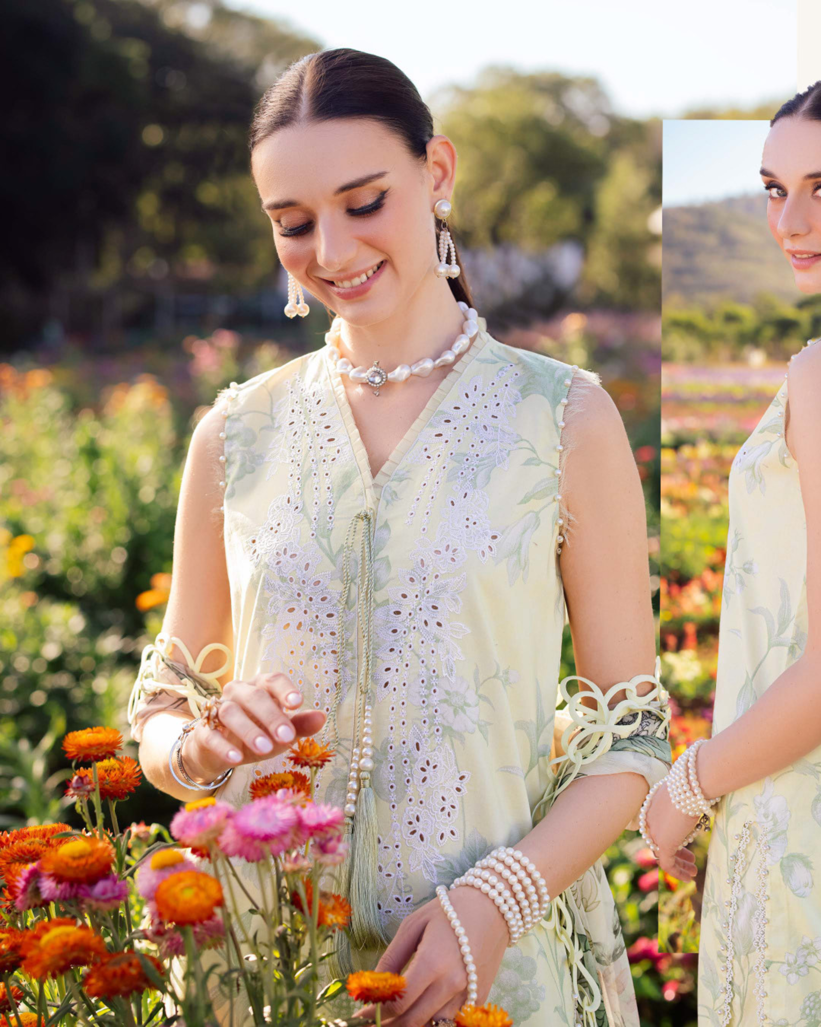 Woman in a light green traditional outfit standing among flowers with a scenic background