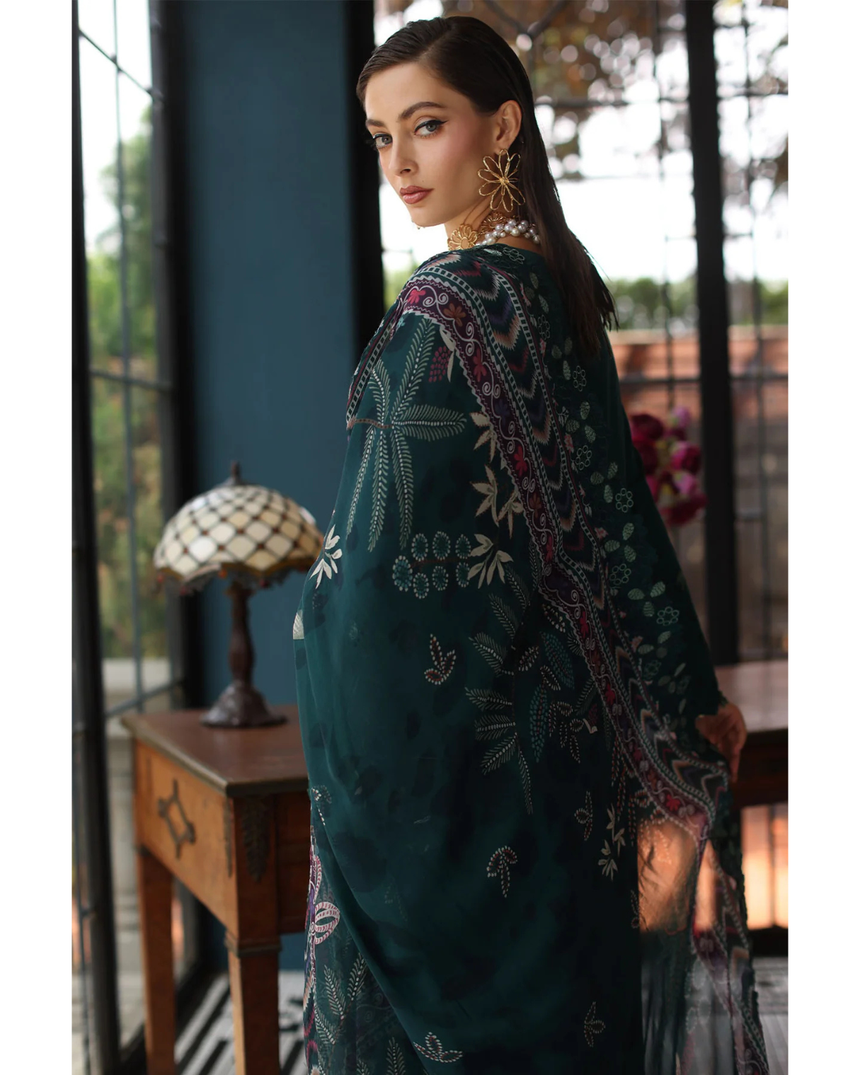 Woman wearing a dark green embroidered traditional outfit in an indoor setting.