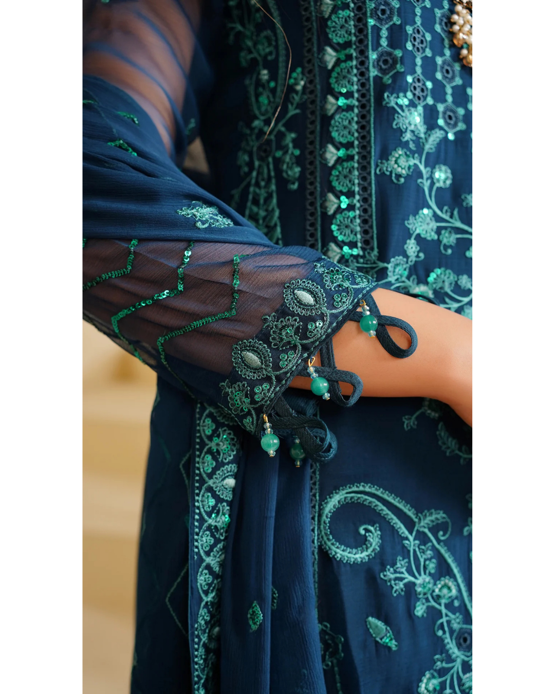 Navy blue embroidered garment with green details on a plain background