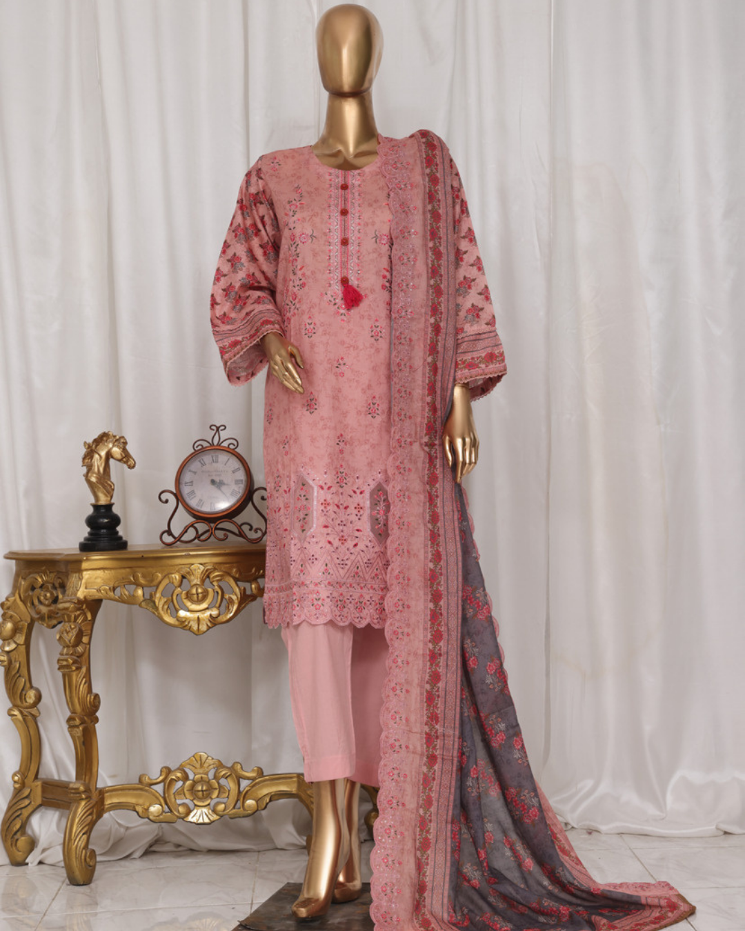 Mannequin wearing a pink embroidered outfit with a matching dupatta against a white curtain background.