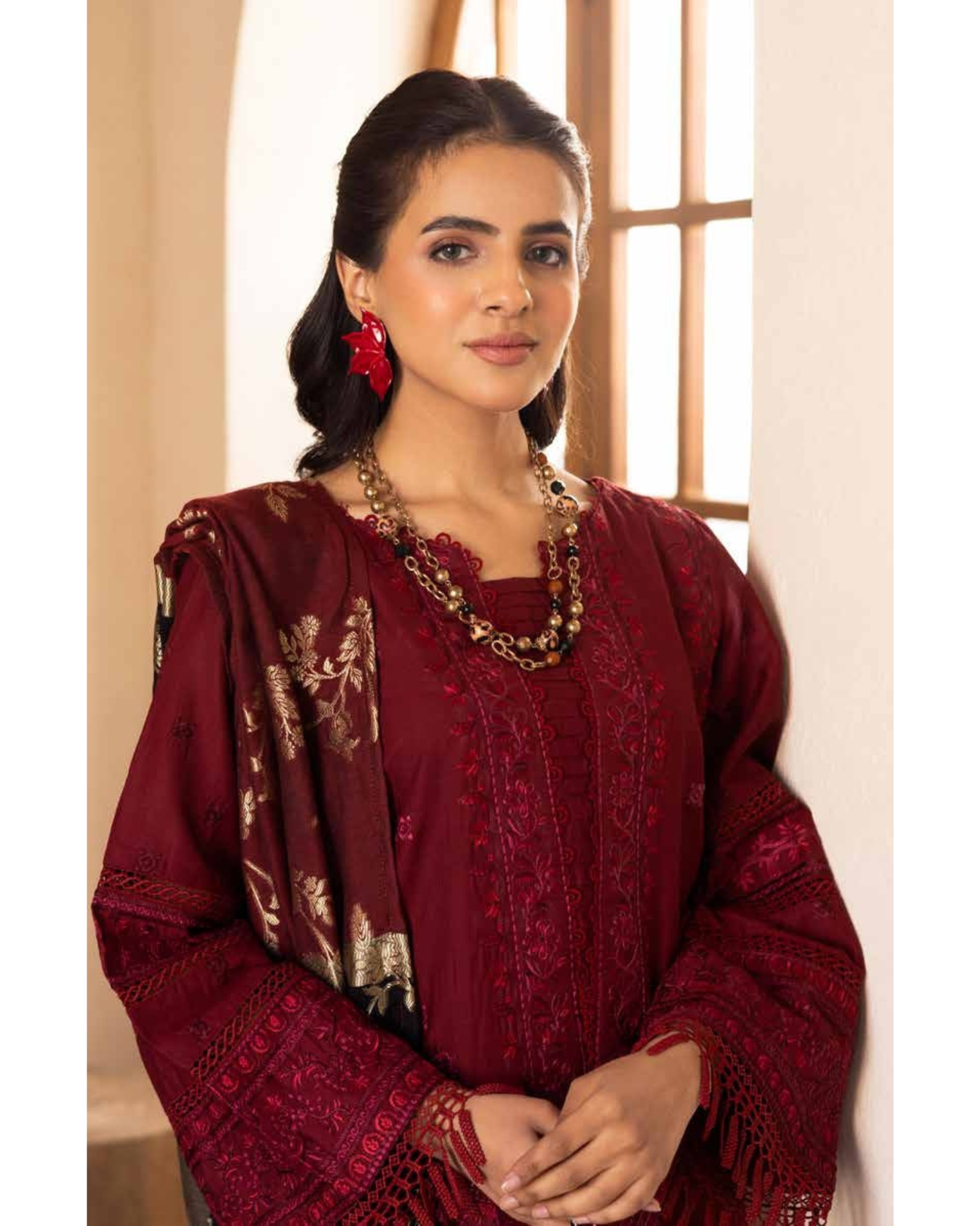Woman wearing a red traditional outfit with intricate patterns indoors.
