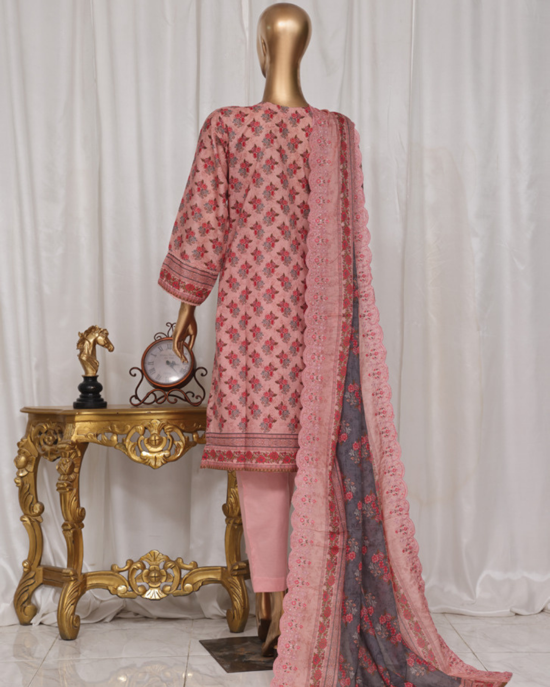 Mannequin wearing a pink and red floral outfit with a matching dupatta against a white curtain background.