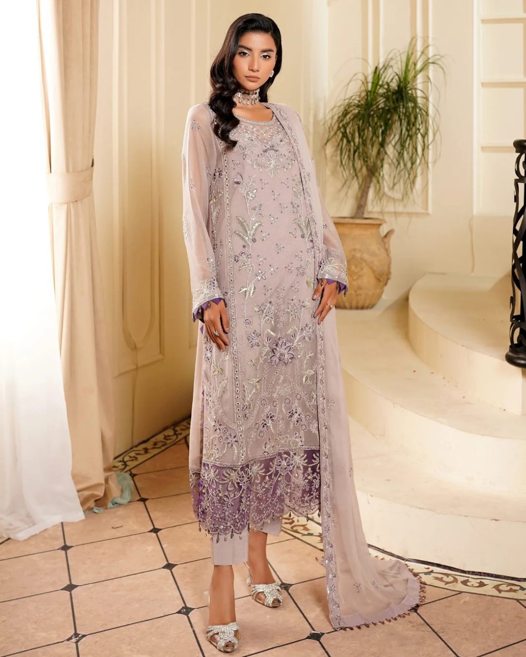 Woman wearing a light purple embroidered dress in an elegant indoor setting.