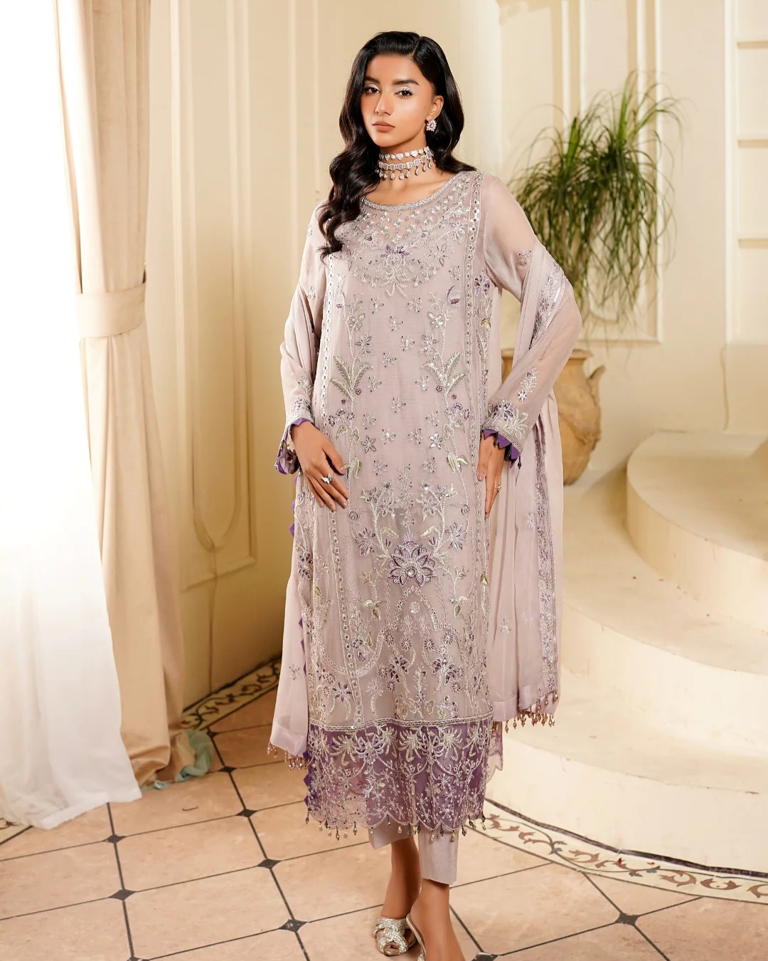 Woman wearing a light purple embroidered dress with a matching dupatta in an elegant indoor setting.