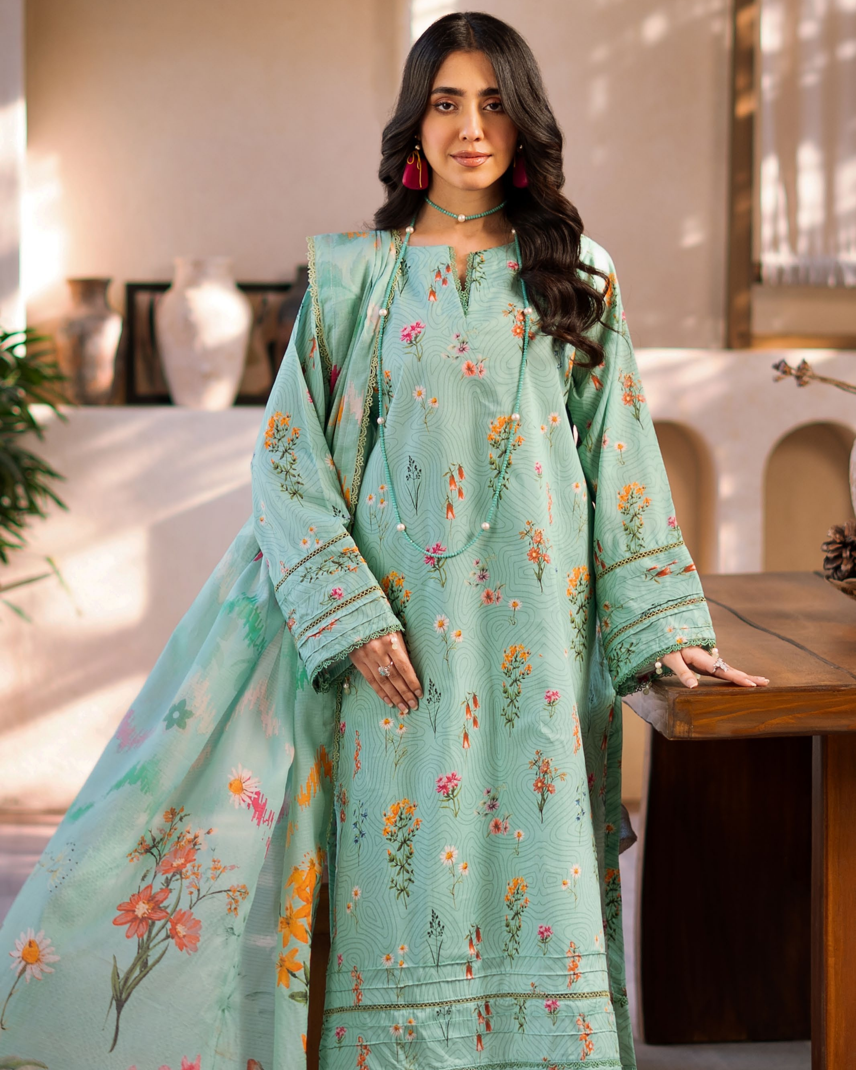 Woman wearing a light blue embroidered traditional outfit indoors.