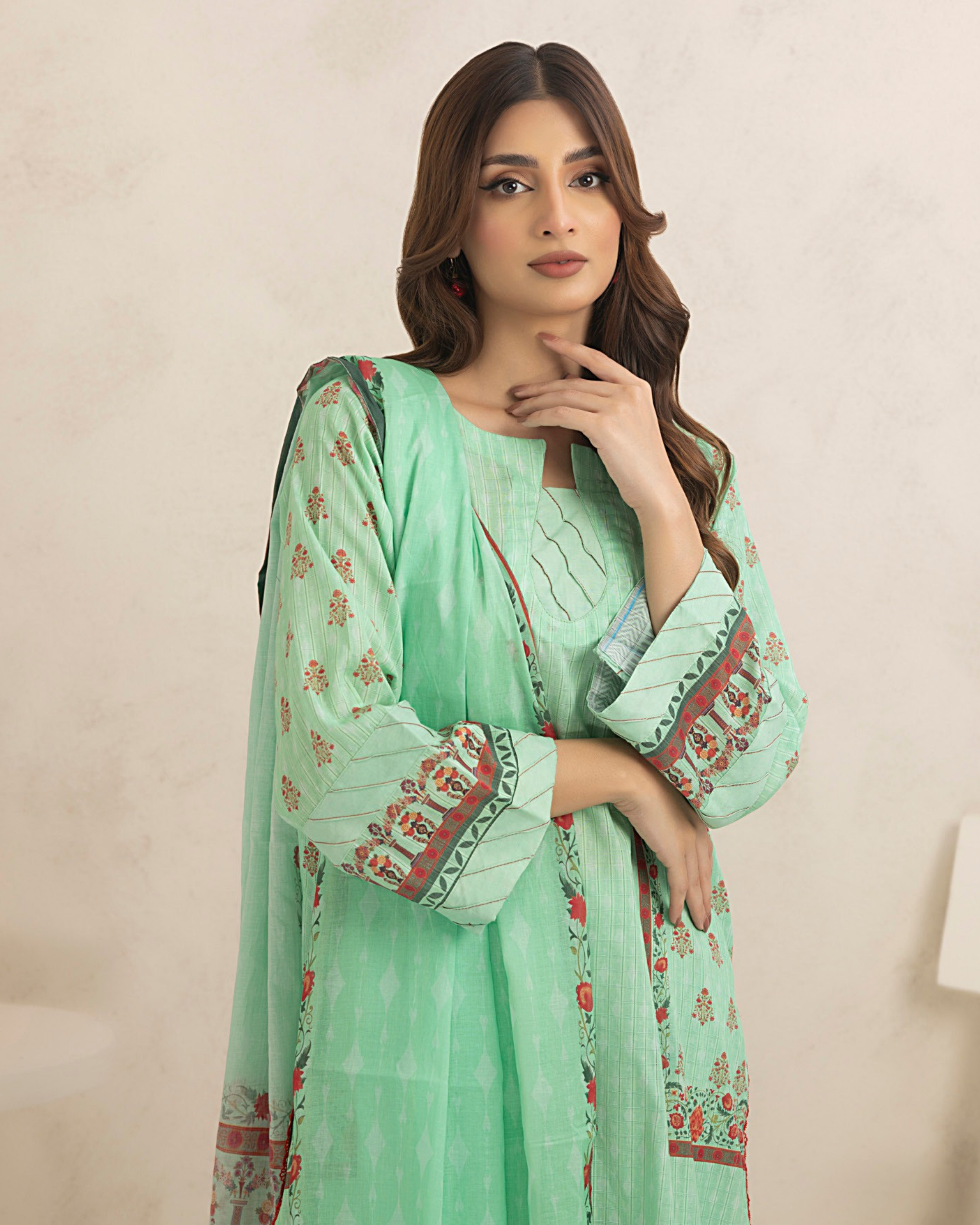Woman wearing a light green traditional outfit with floral patterns on a beige background
