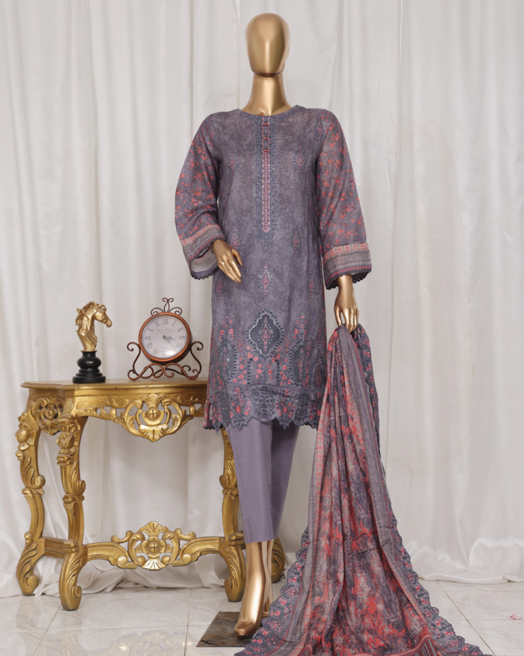 Mannequin wearing a patterned outfit with a scarf on a white background