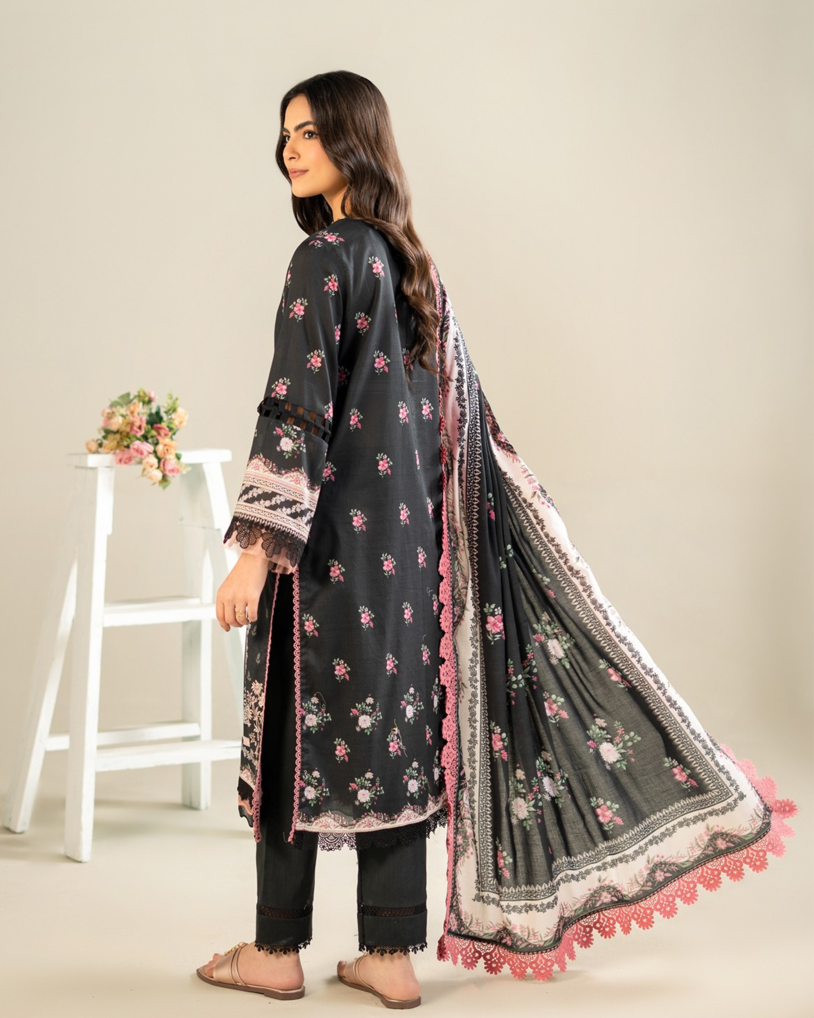 Woman wearing a black floral embroidered outfit with a white background