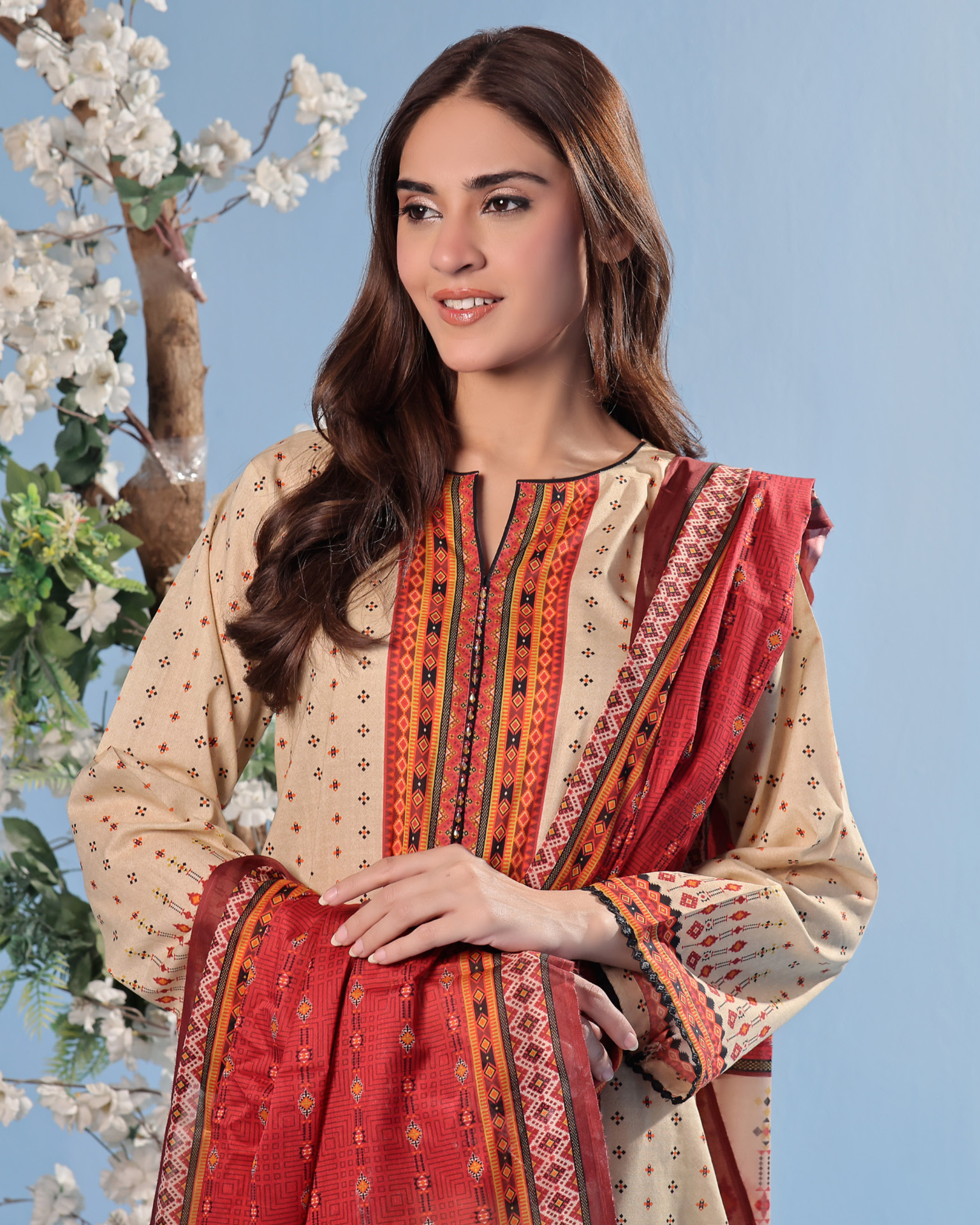 Woman wearing a traditional outfit with a red and beige pattern against a blue background