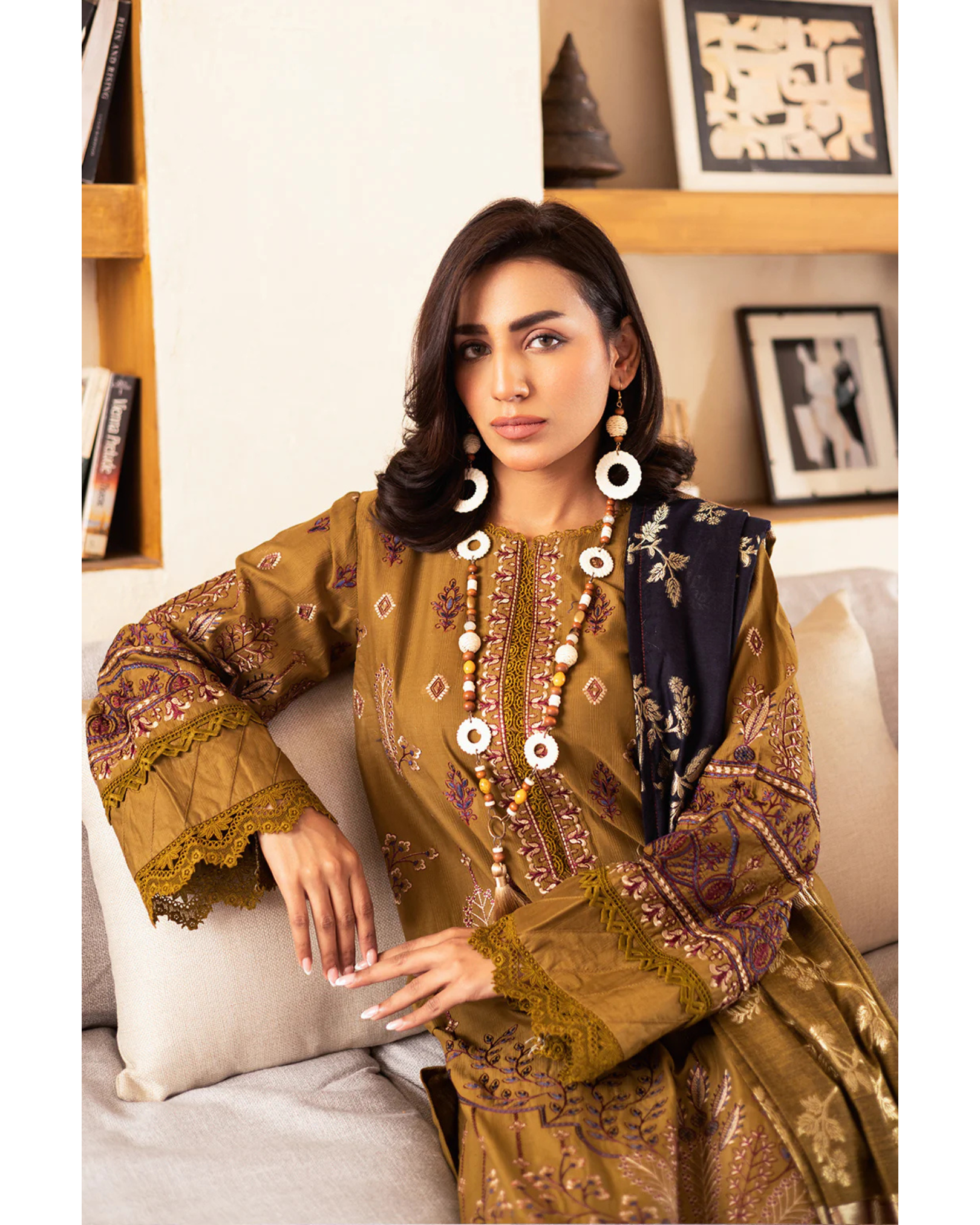 Woman in traditional embroidered outfit sitting on a couch in a home setting