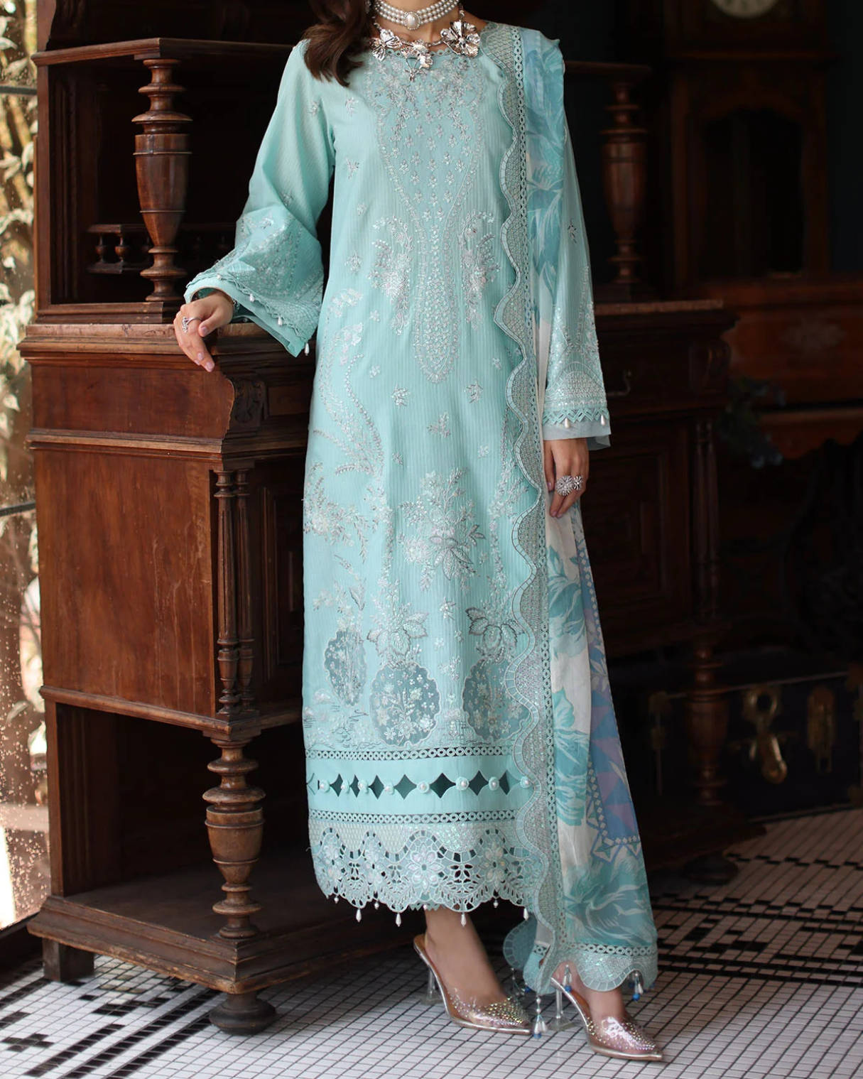 Woman wearing a light blue embroidered dress in an indoor setting.