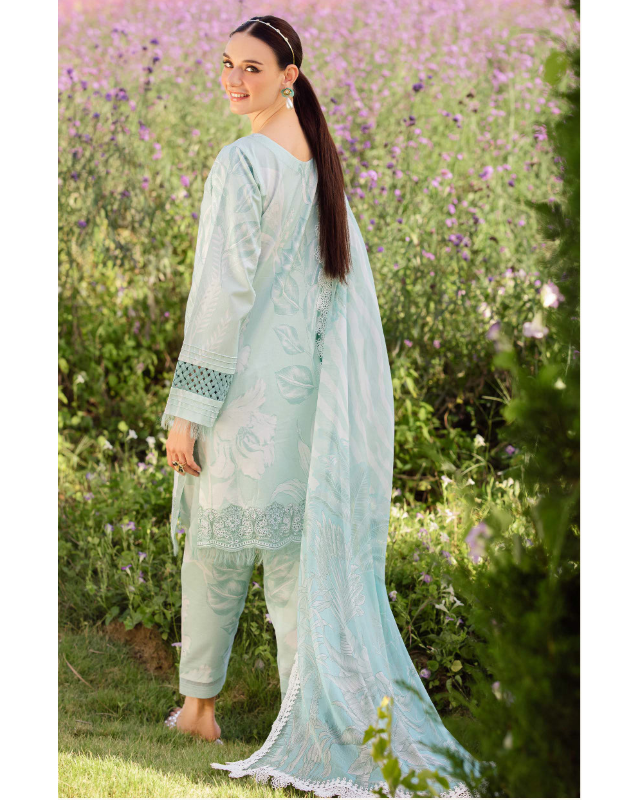 Woman in a light blue traditional outfit standing in a field of flowers