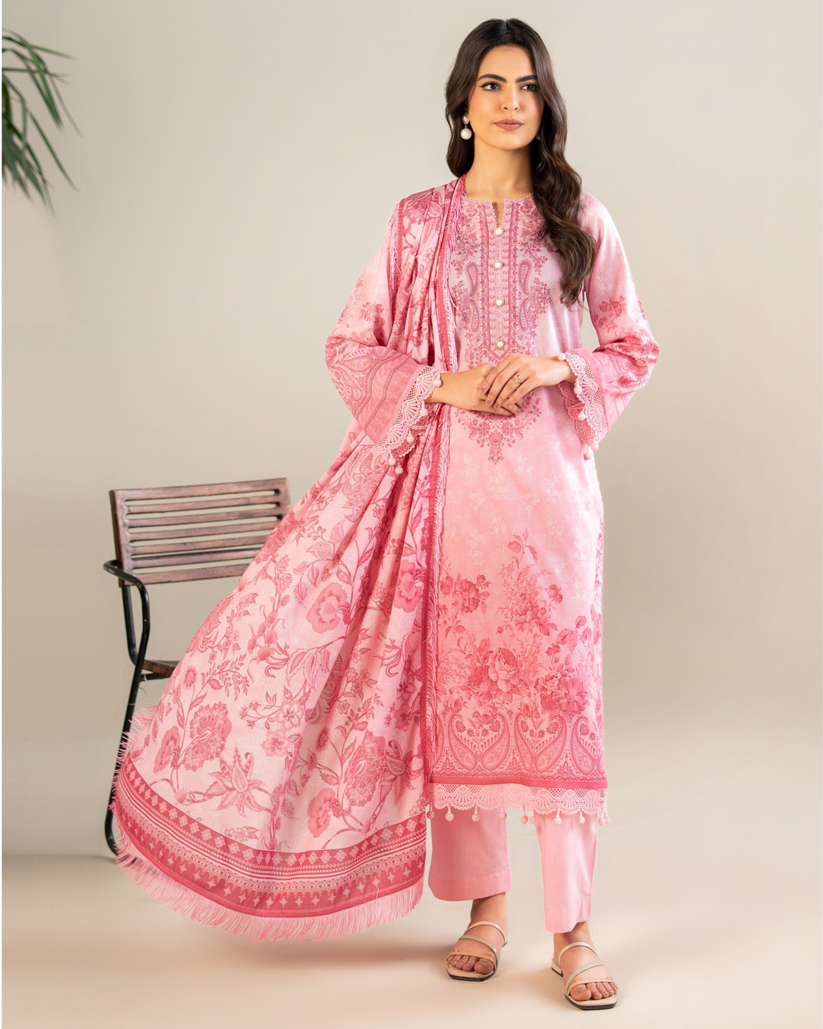Woman wearing a pink traditional outfit with floral patterns on a beige background