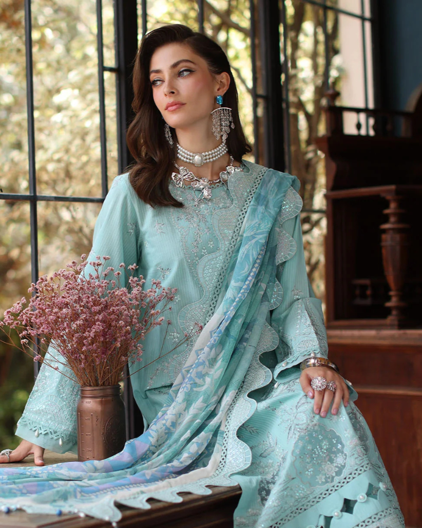Woman in a light blue embroidered outfit sitting on a wooden bench indoors.