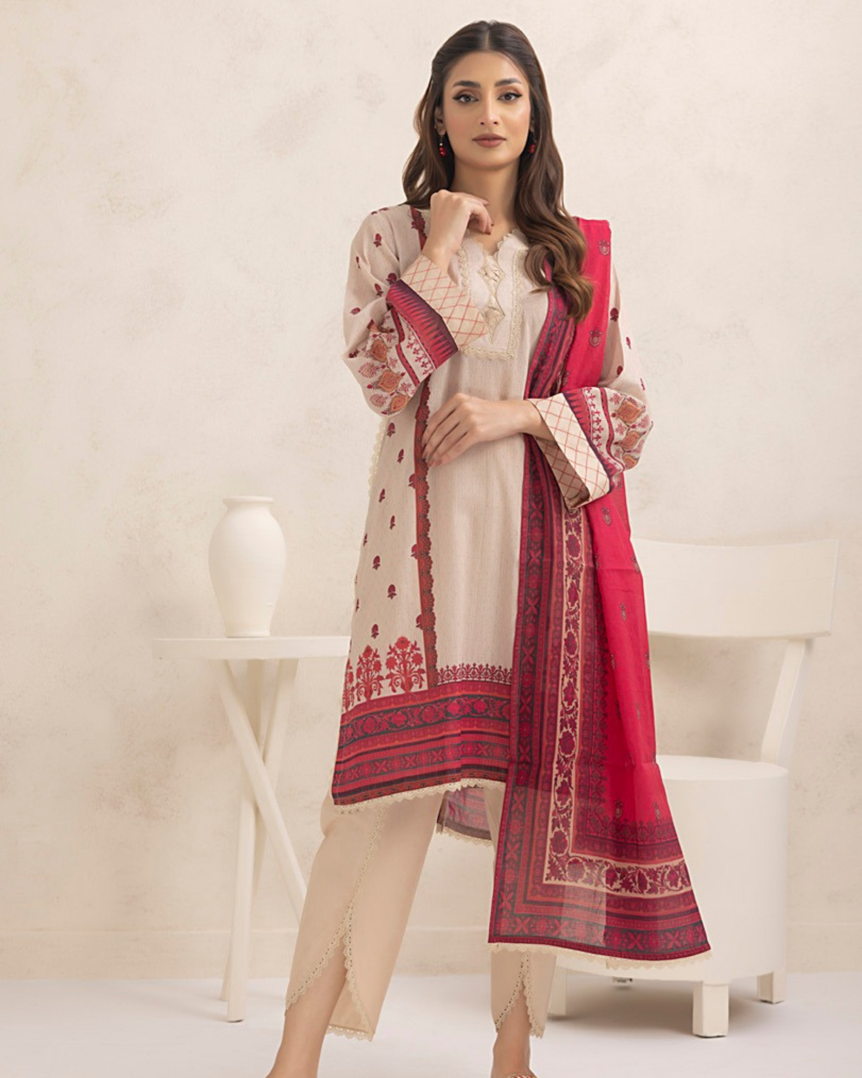 Woman wearing a red and beige traditional outfit with a matching dupatta against a white background