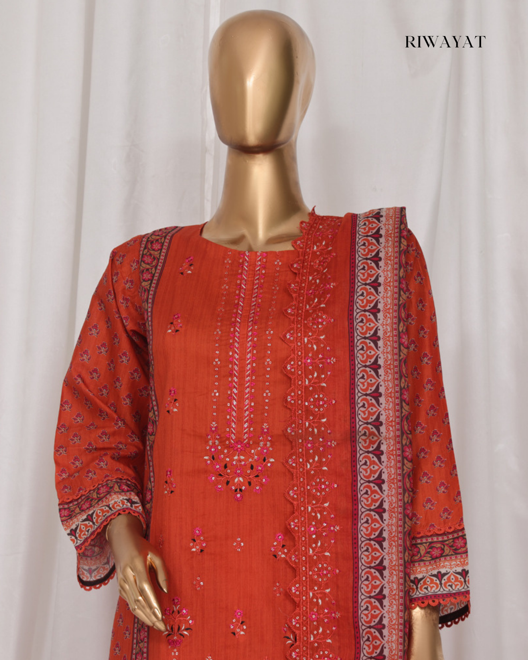 Red embroidered traditional outfit on a mannequin with 'RIWAYAT' branding.