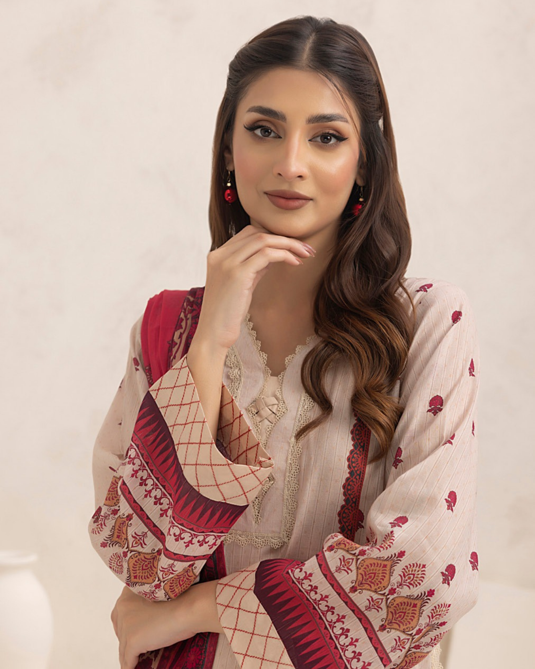 Woman wearing a traditional outfit with red and white patterns on a plain background