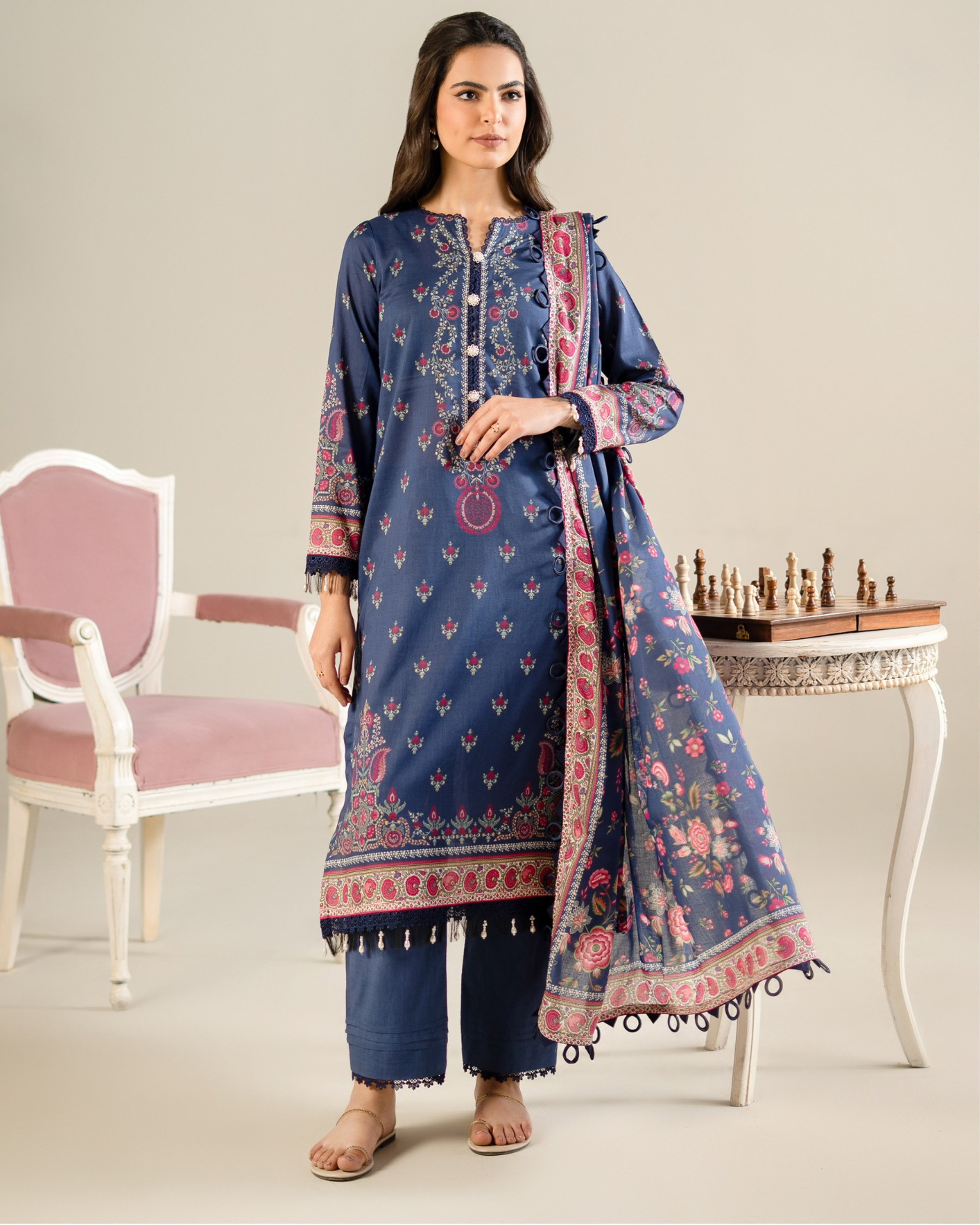 Woman wearing a blue embroidered outfit with a matching dupatta in a minimalistic setting.