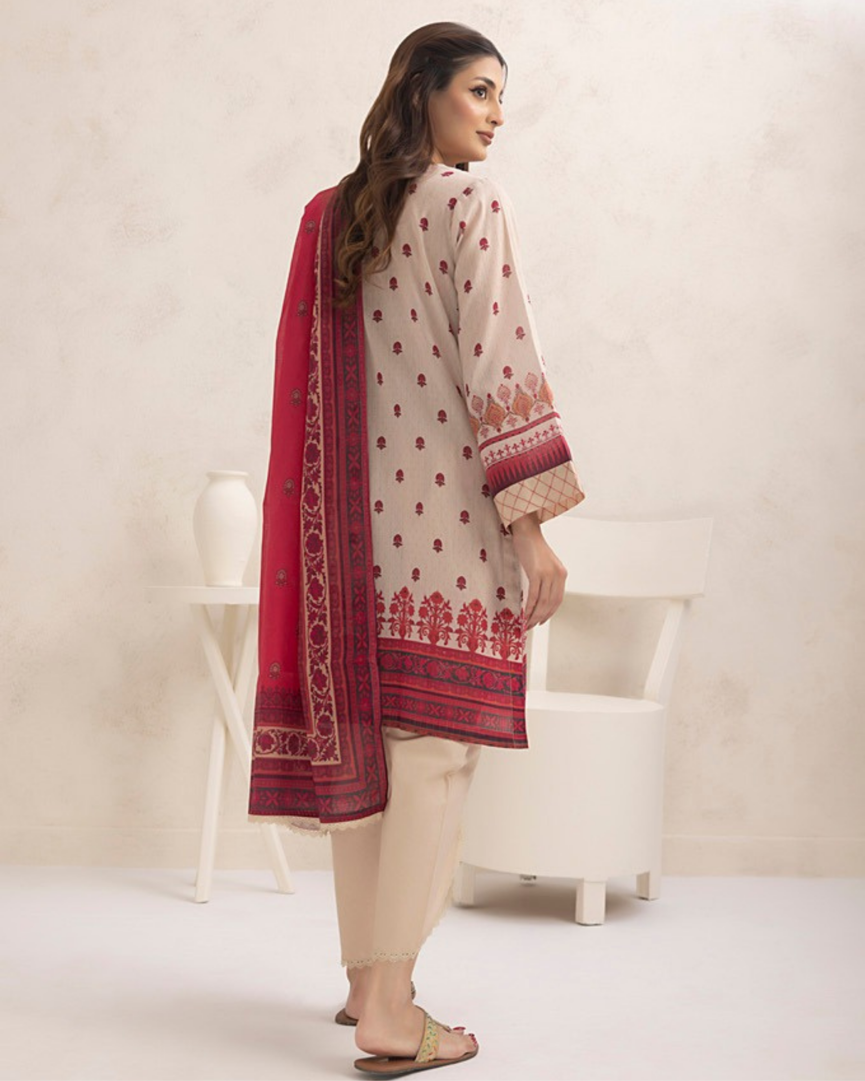 Woman wearing a cream and red traditional outfit with a matching dupatta on a white background