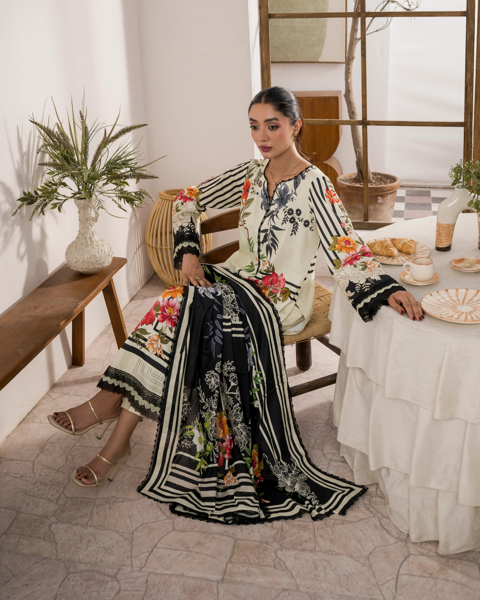 Woman in a floral dress sitting at a table with a decorative setting.