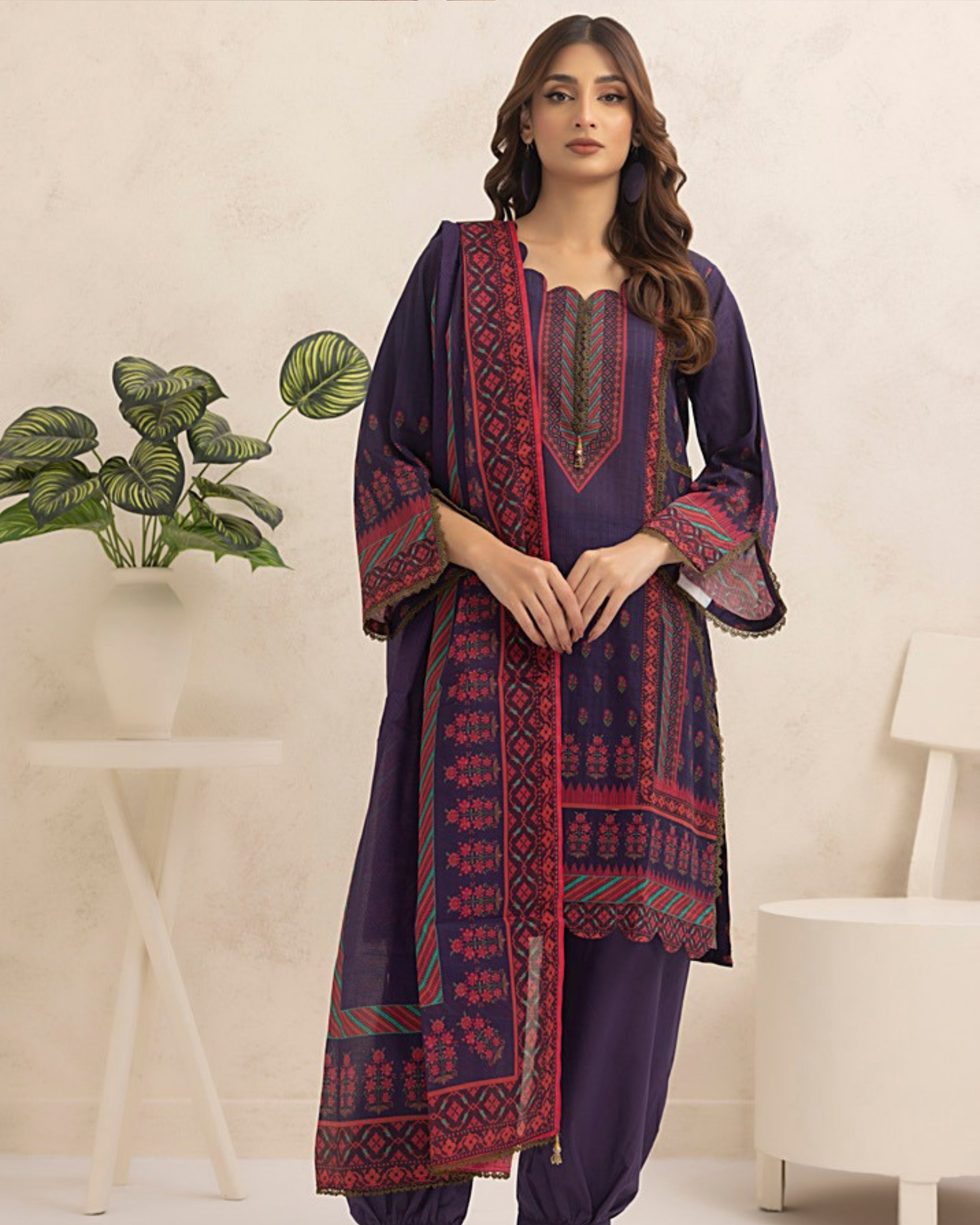 Woman wearing a traditional outfit with a patterned dupatta in a minimalistic setting