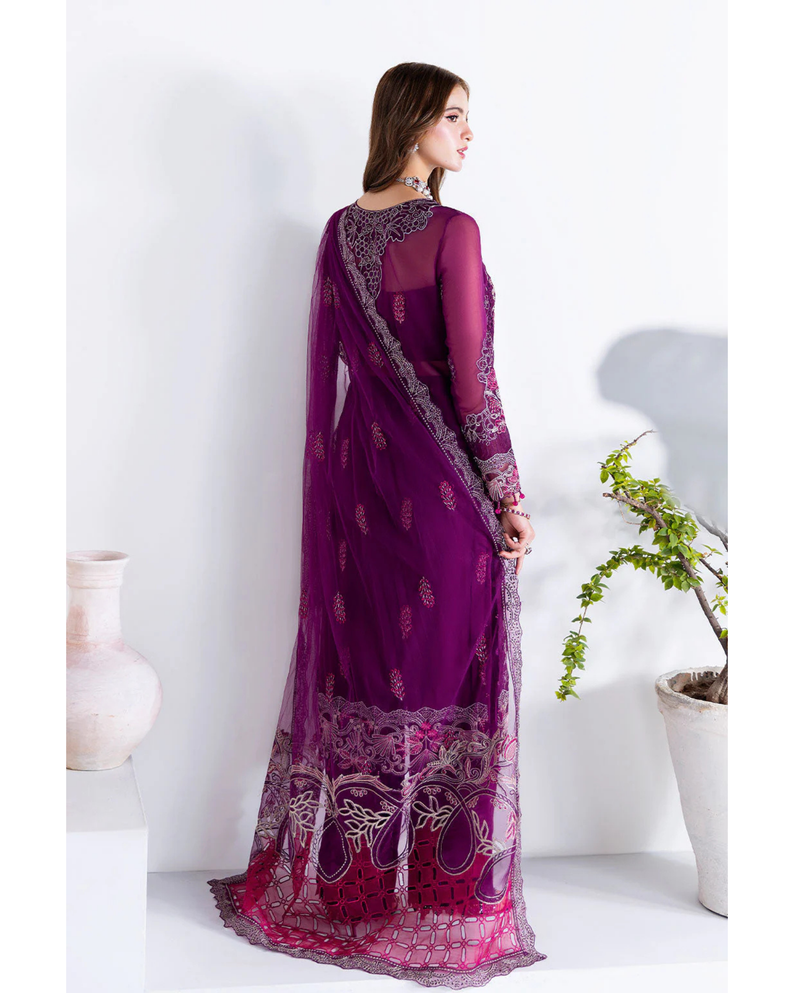 Woman wearing a purple saree with intricate designs on a white background