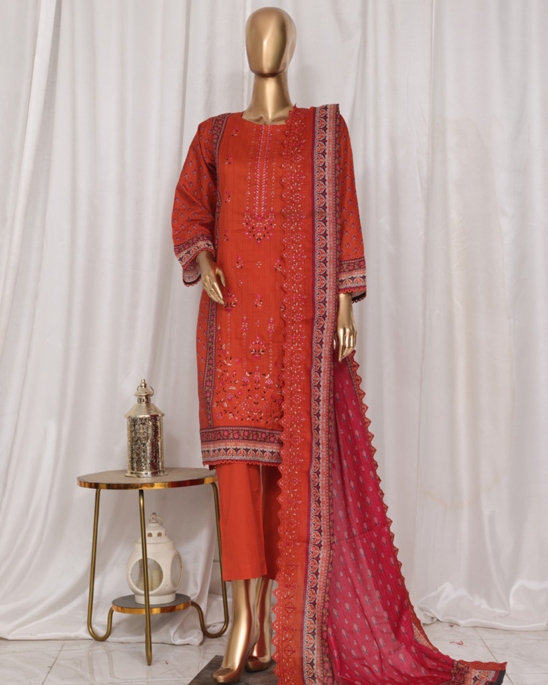 Red embroidered traditional outfit with a mannequin against a white curtain background