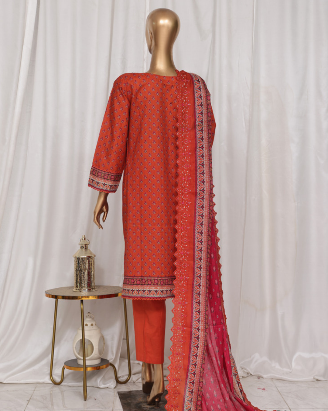 Red patterned dress with matching dupatta on a mannequin against a white curtain background