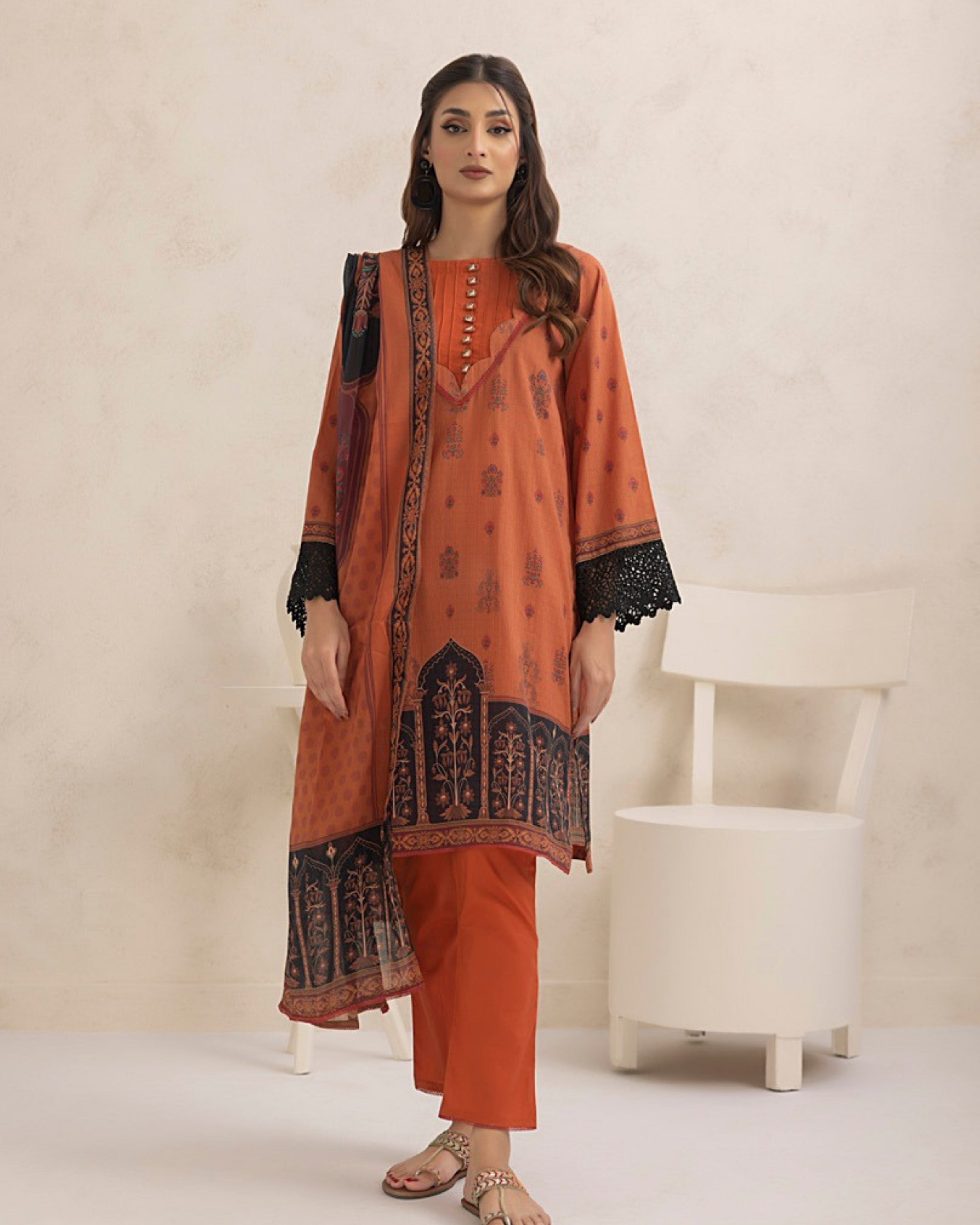 Woman wearing an orange traditional outfit with black patterns against a white background