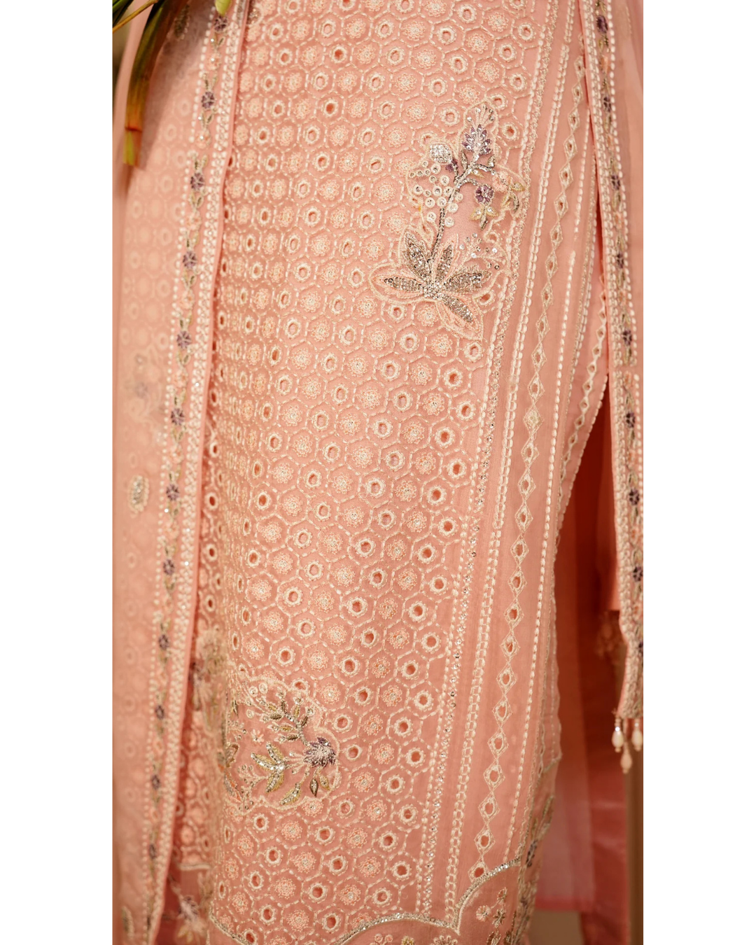 Pink embroidered fabric with floral patterns on a plain background