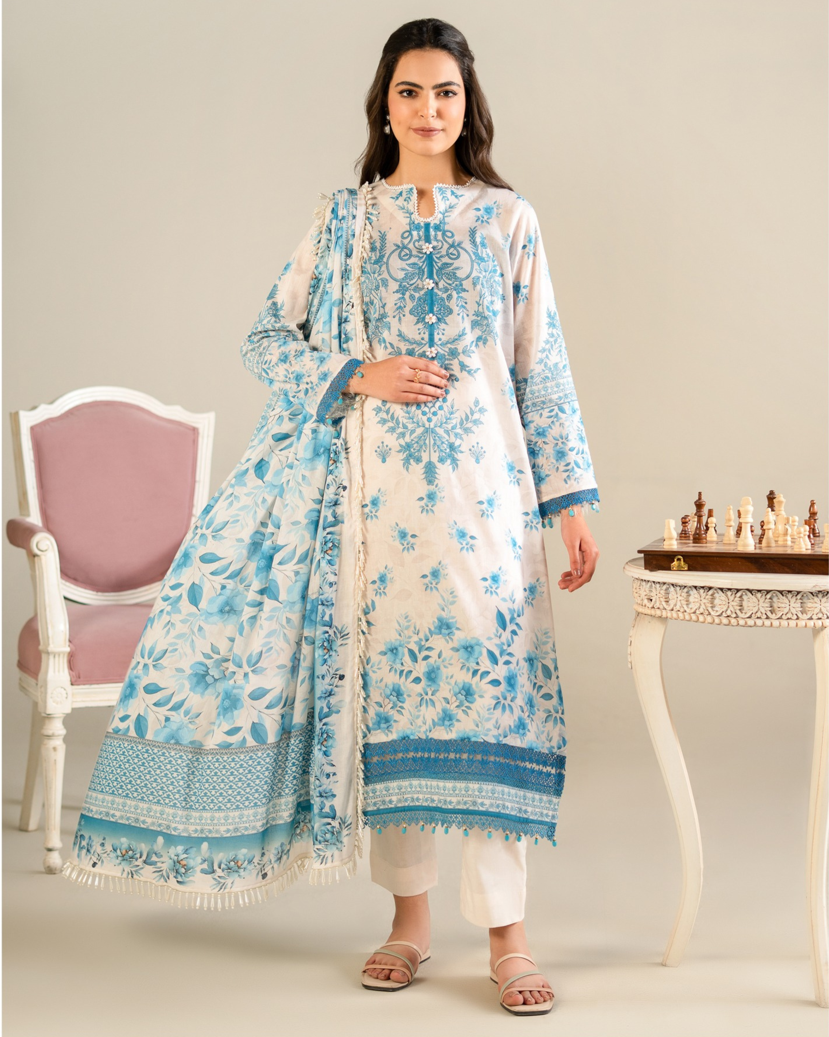 Woman wearing a blue and white floral outfit with a matching shawl in a room setting.