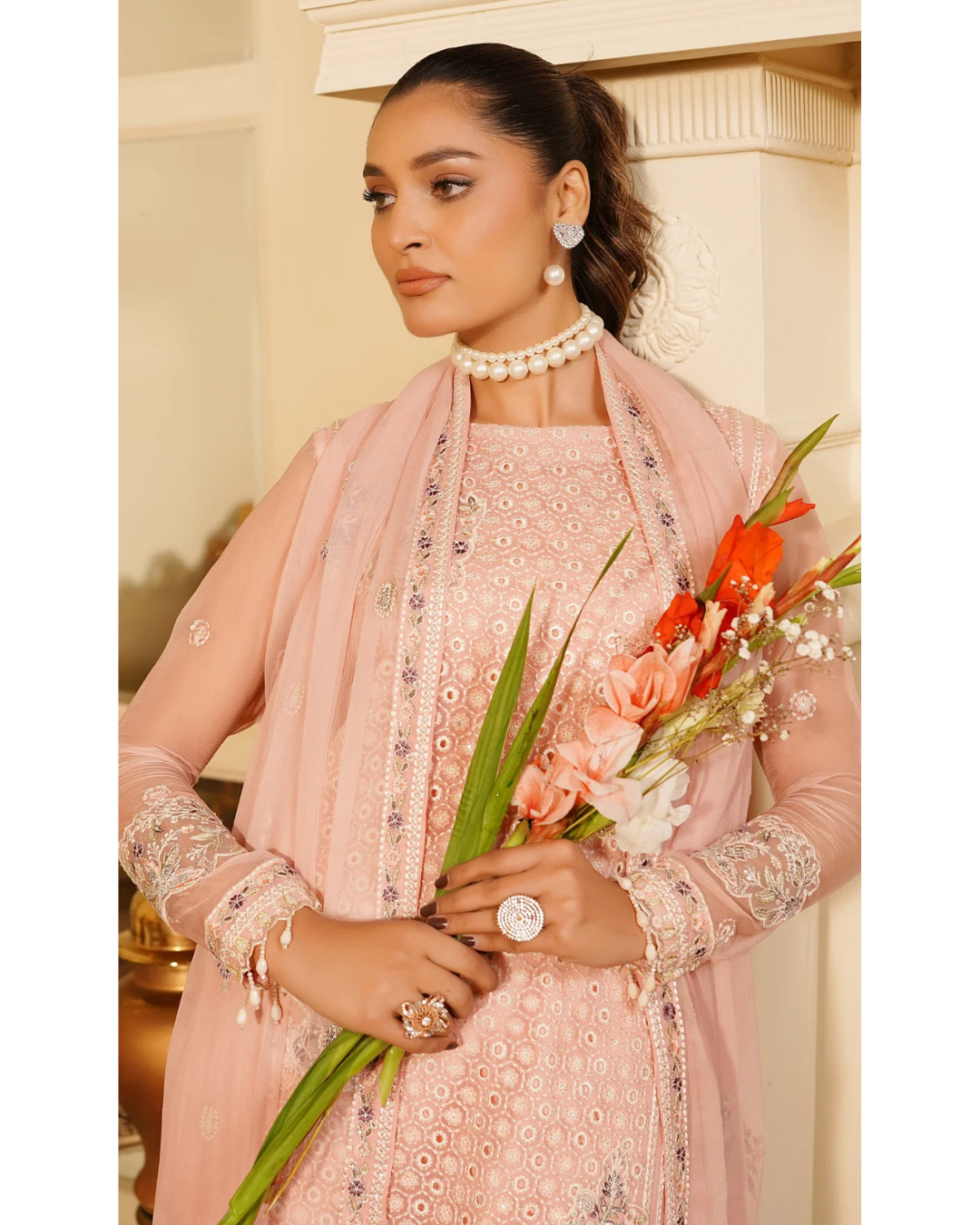 Woman in a pink traditional outfit holding flowers indoors