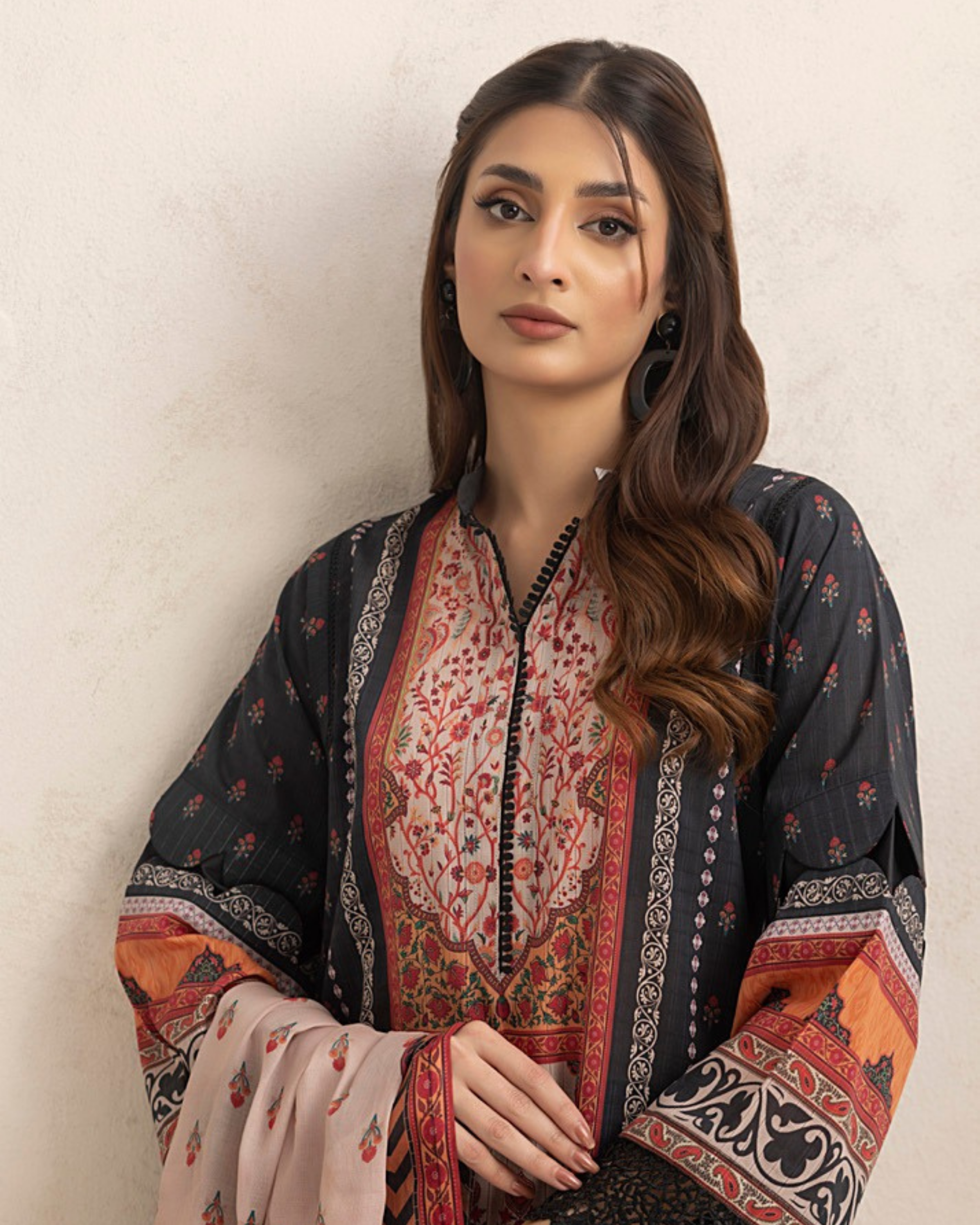Woman wearing a traditional embroidered outfit against a plain background