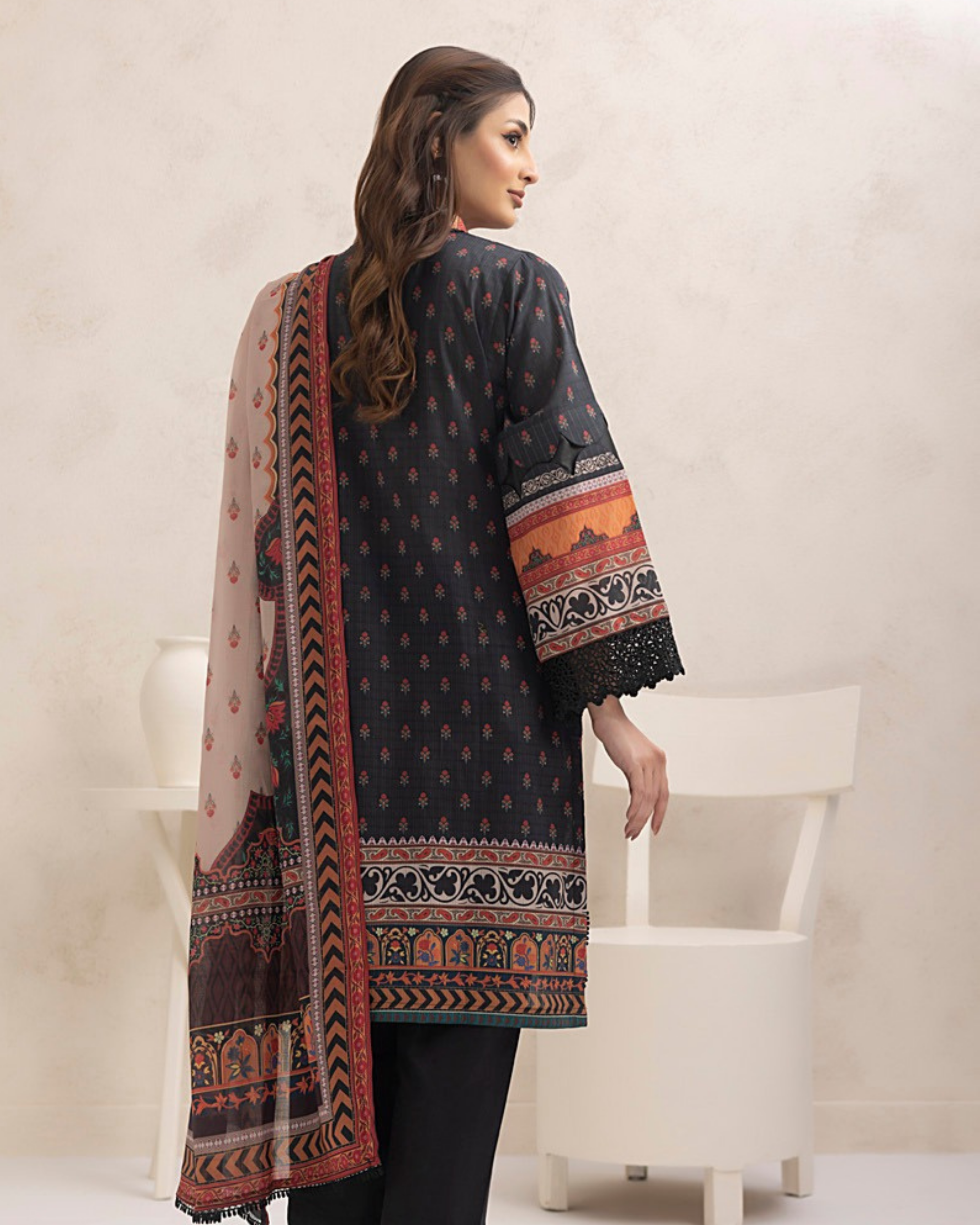 Woman wearing a patterned black shirt with a long scarf in a minimalistic setting