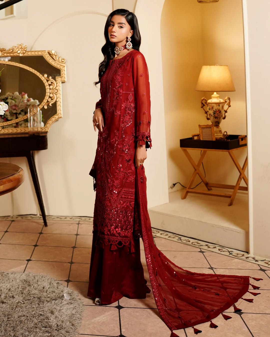 Woman in a red embroidered dress standing in a decorated room.
