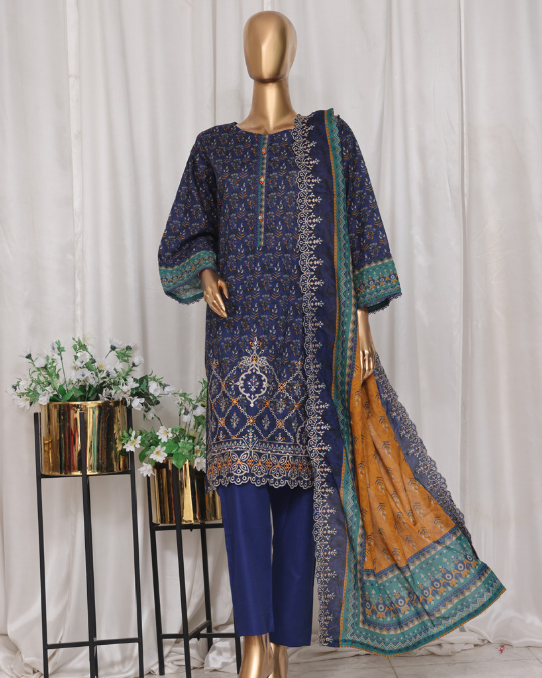 Mannequin wearing a blue embroidered outfit with a matching dupatta against a white curtain background.