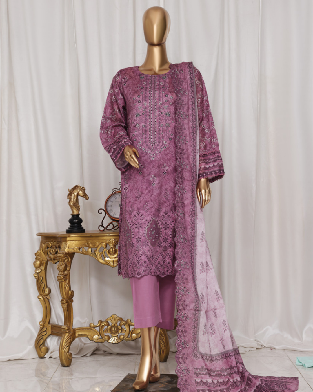 Mannequin wearing a pink embroidered outfit with a matching dupatta against a white curtain background.