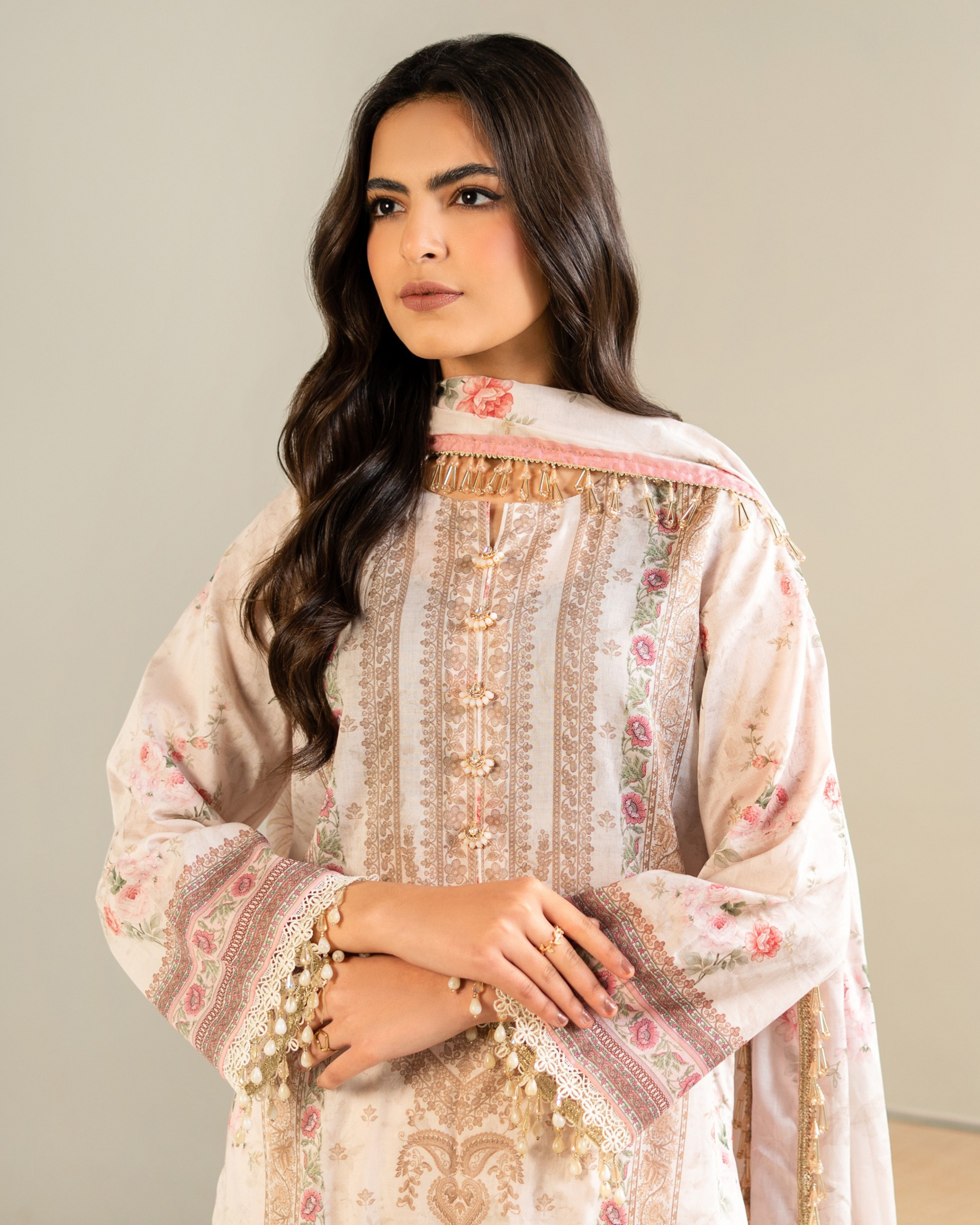Woman wearing a traditional embroidered outfit with a neutral background