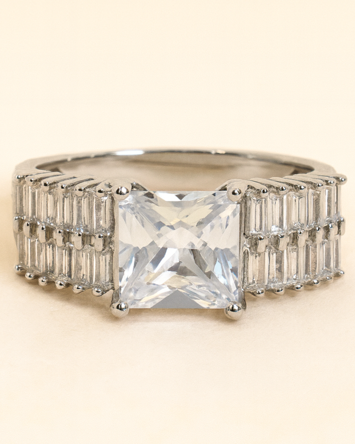 Ring with a large central gemstone and smaller stones on a beige background