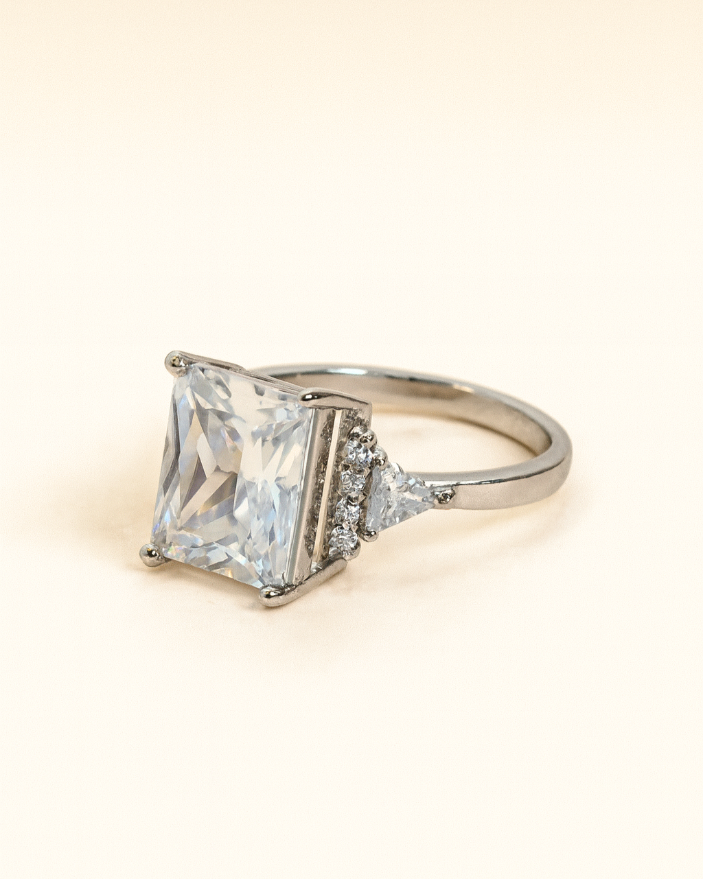 Diamond ring with a square-cut center stone on a beige background