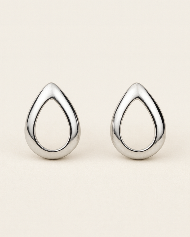 Pair of silver teardrop-shaped earrings on a beige background
