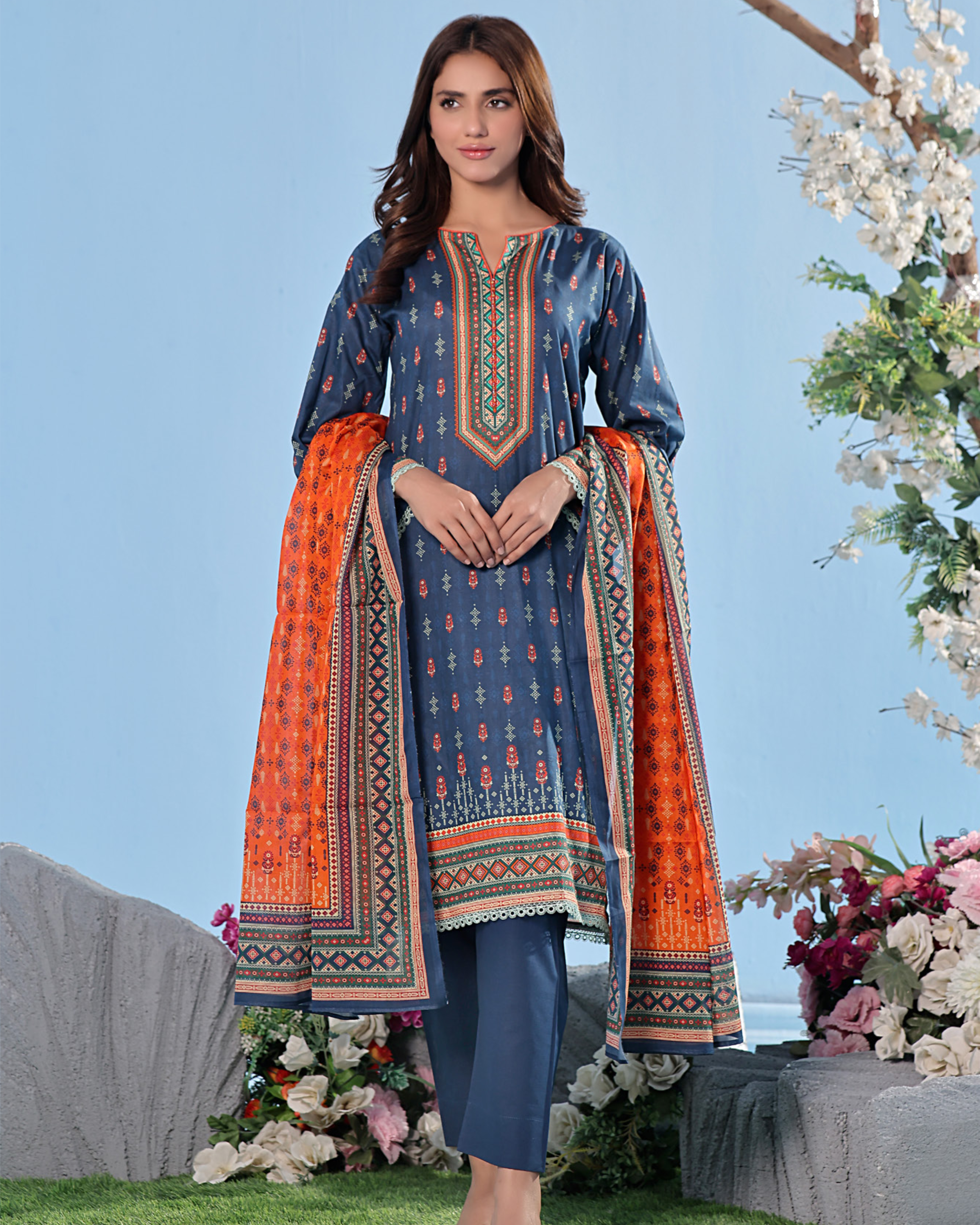 Woman wearing a blue and orange traditional outfit with a floral background