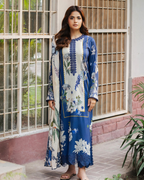 Woman wearing a blue and white floral dress standing in front of a window.