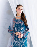 Woman wearing a blue embroidered traditional outfit with a white curtain background
