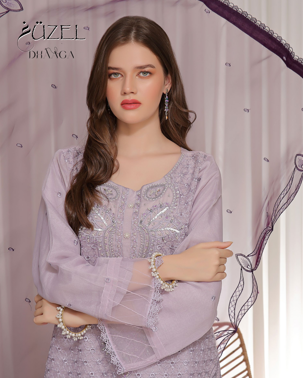 Woman wearing a purple embroidered outfit with 'Uzziel' branding in the background
