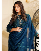 Woman wearing a blue saree with intricate designs indoors.