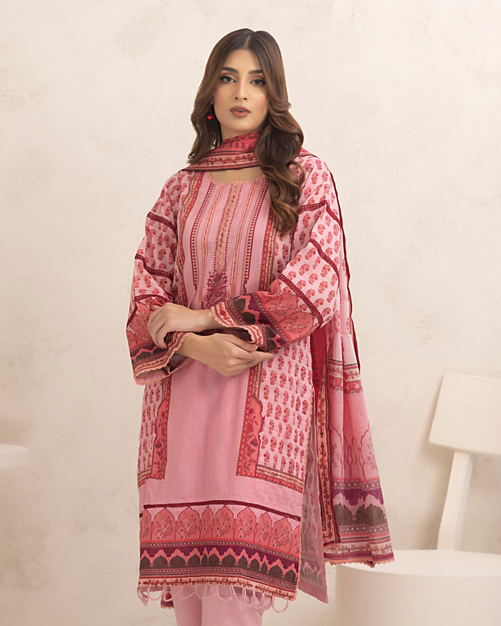 Woman wearing a pink and red patterned traditional outfit on a white background