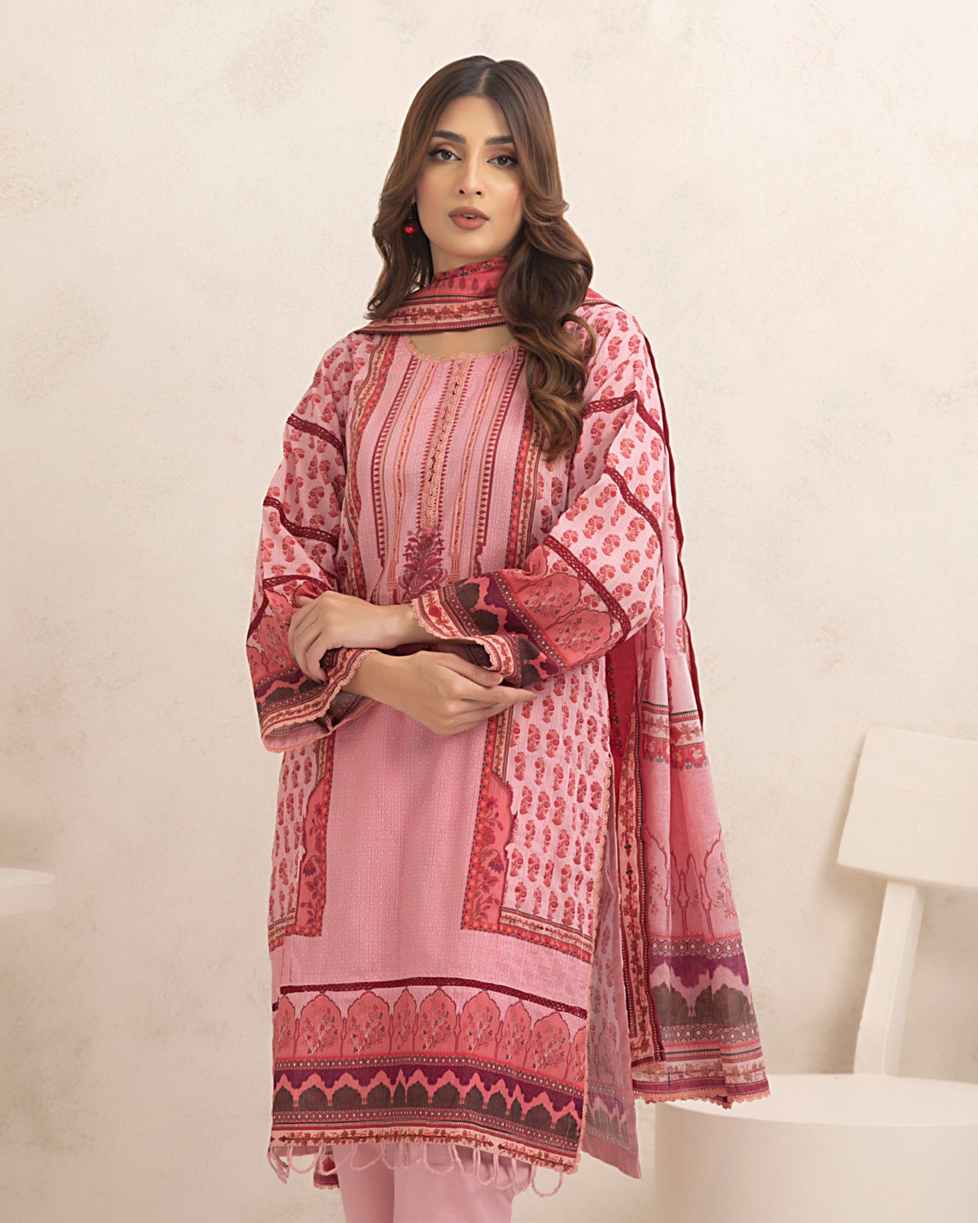 Woman wearing a pink and red patterned traditional outfit on a white background