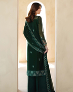 Woman wearing a dark green embroidered traditional outfit in a neutral setting